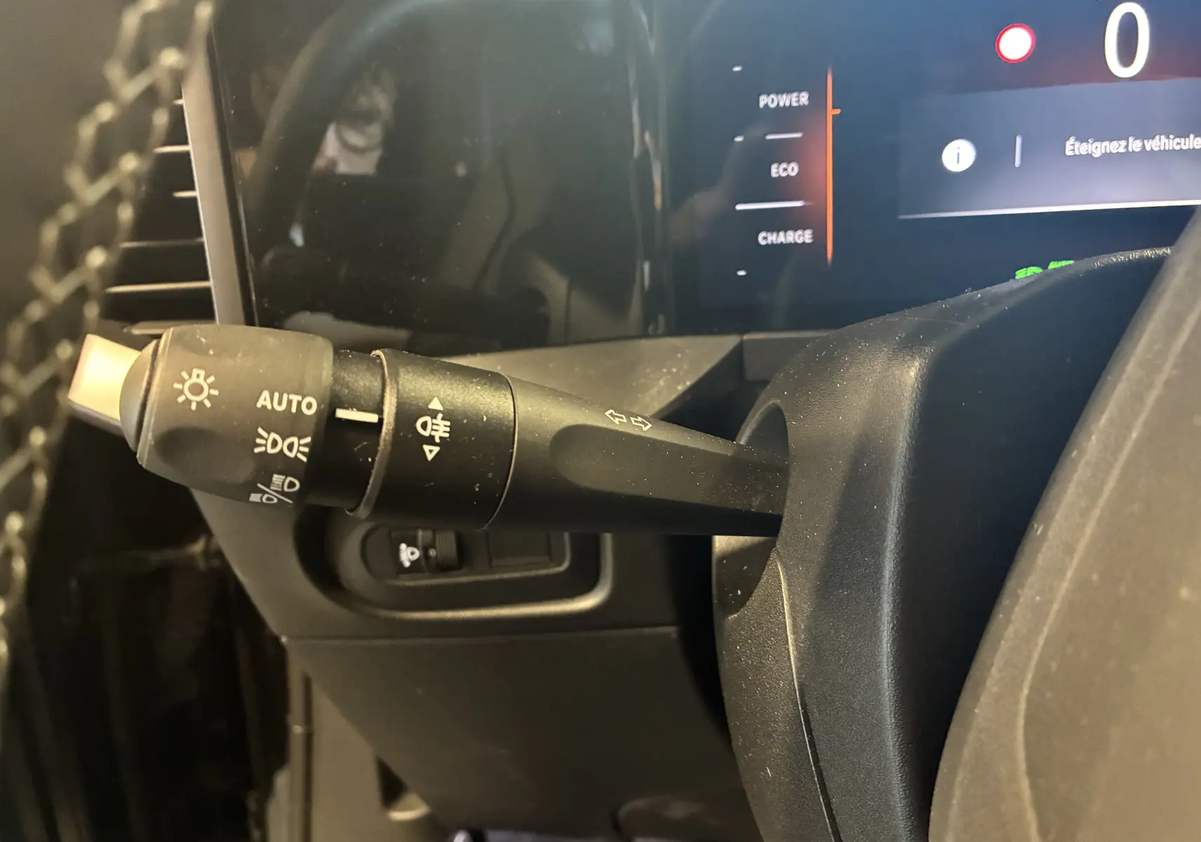 Gros plan sur la manette de clignotants et phares à gauche du volant dans l’habitacle noir de l’Opel Mokka 2025 hybride.