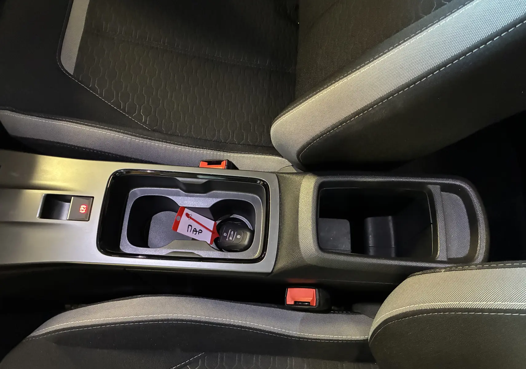 Vue intérieure rapprochée du coffre à gobelets central et des sièges noirs avec surpiqûres grises de l’Opel Mokka 2025.