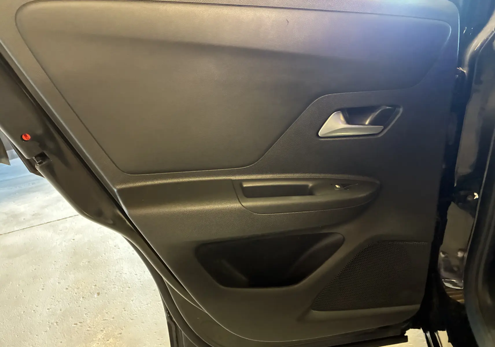 Vue intérieure de la porte arrière droite noire de l’Opel Mokka 1.2 Turbo Hybrid 2025 avec poignée argentée et commande de fenêtre.