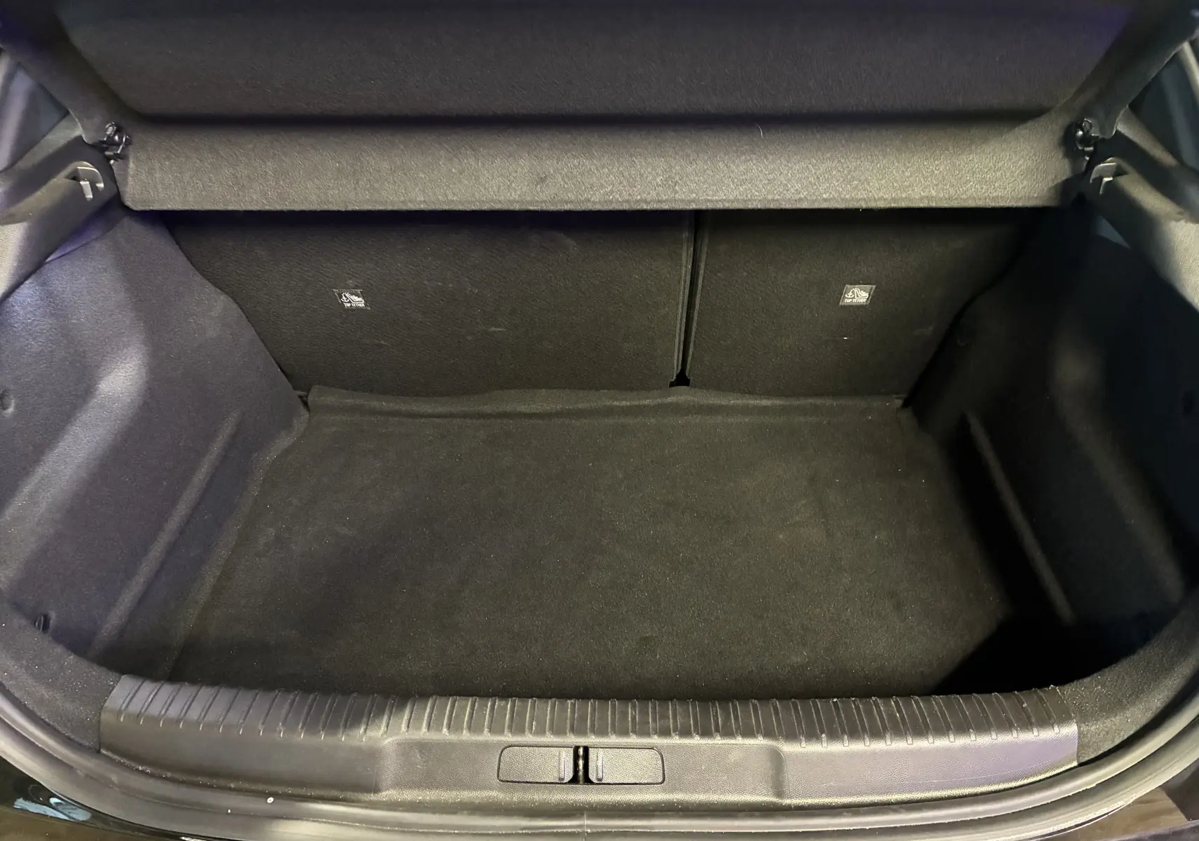 Coffre ouvert vu de face de l’Opel Mokka 2025 noir, version hybride, montrant un espace de chargement vide et propre.