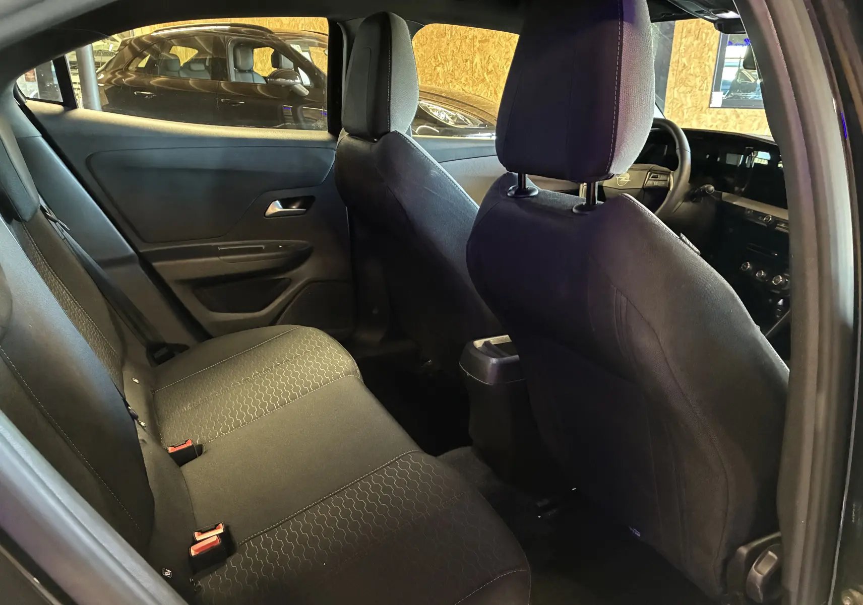 Vue intérieure arrière gauche de l’Opel Mokka 2025 noire, montrant les sièges arrière et le tableau de bord à l’avant.