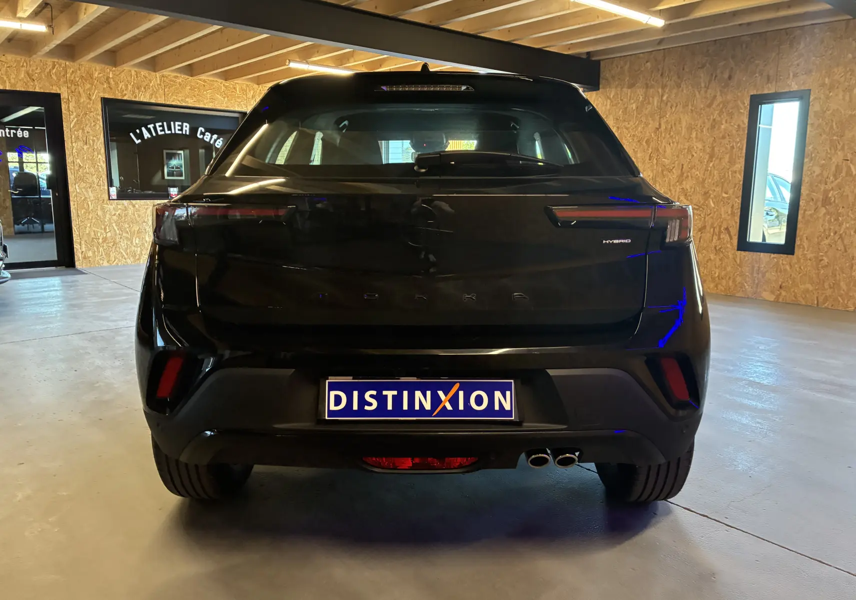Vue arrière d'un Opel Mokka noir hybride 2025, avec feux arrière LED et double sortie d'échappement visible en intérieur.