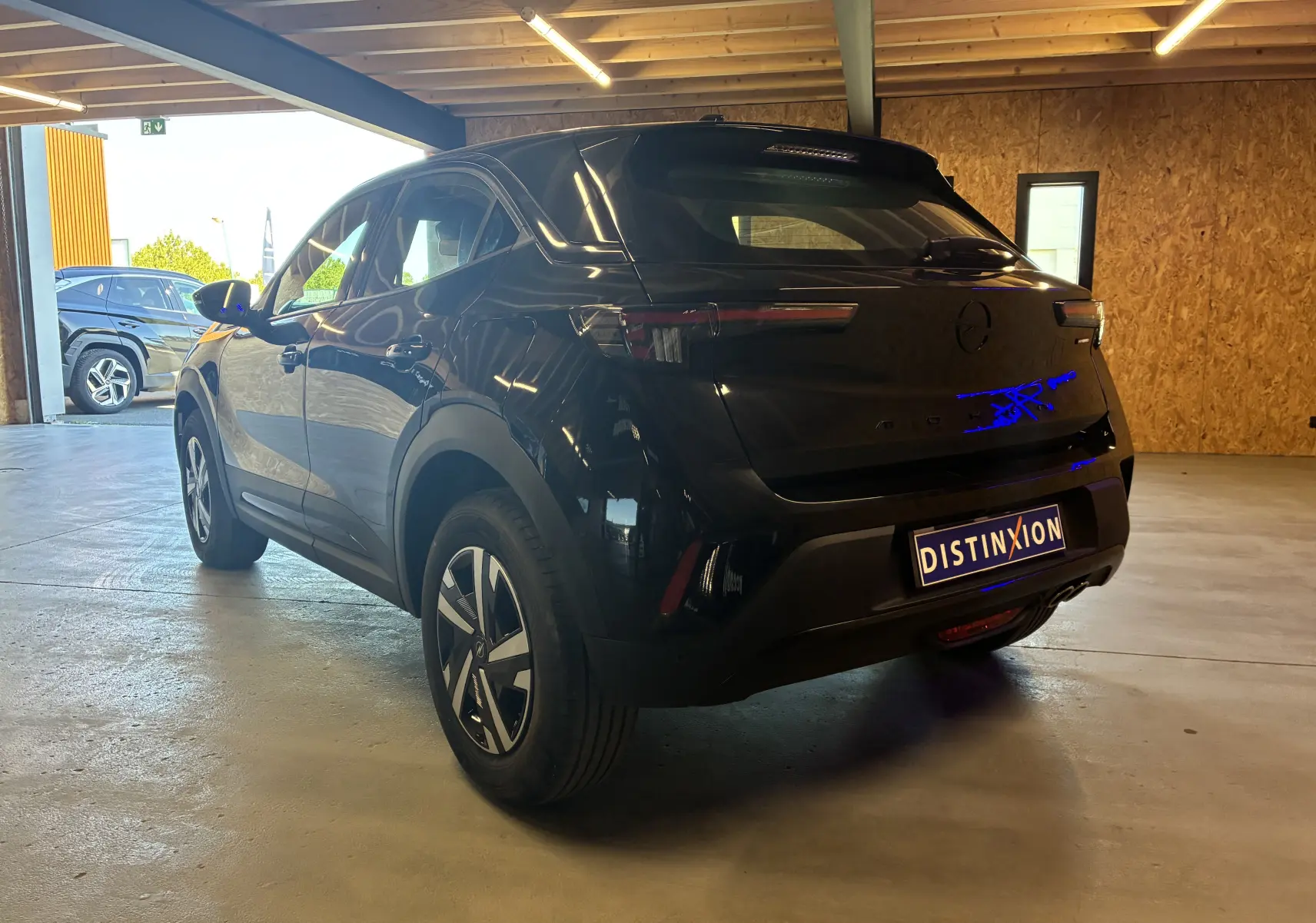 Opel Mokka 2025 noir en 3/4 arrière droit, avec feux arrière fins et jantes au design moderne dans un garage.