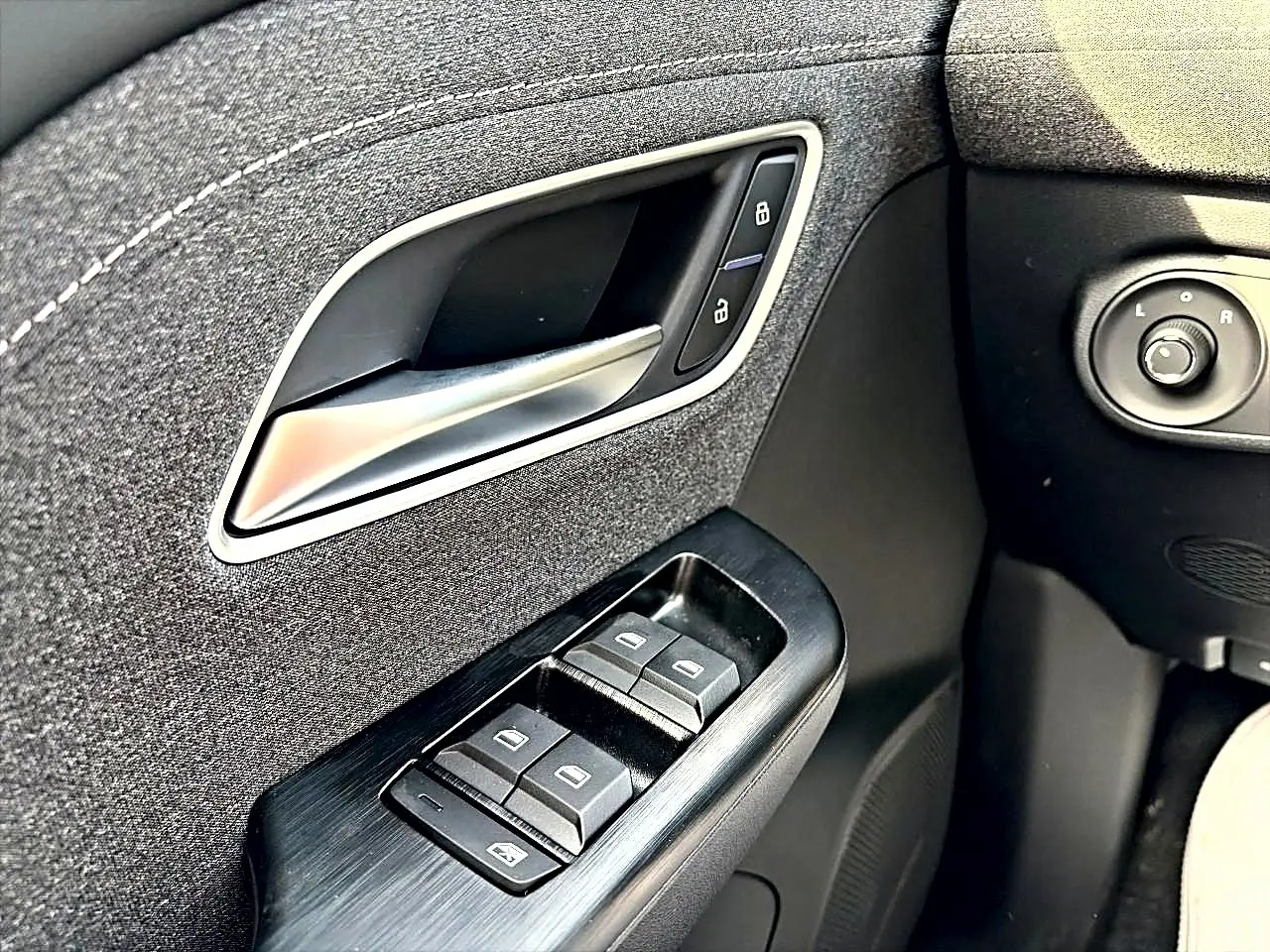 Gros plan sur la commande des vitres et poignée intérieure côté gauche du MG Motor ZS Cosmic Silver 2026.