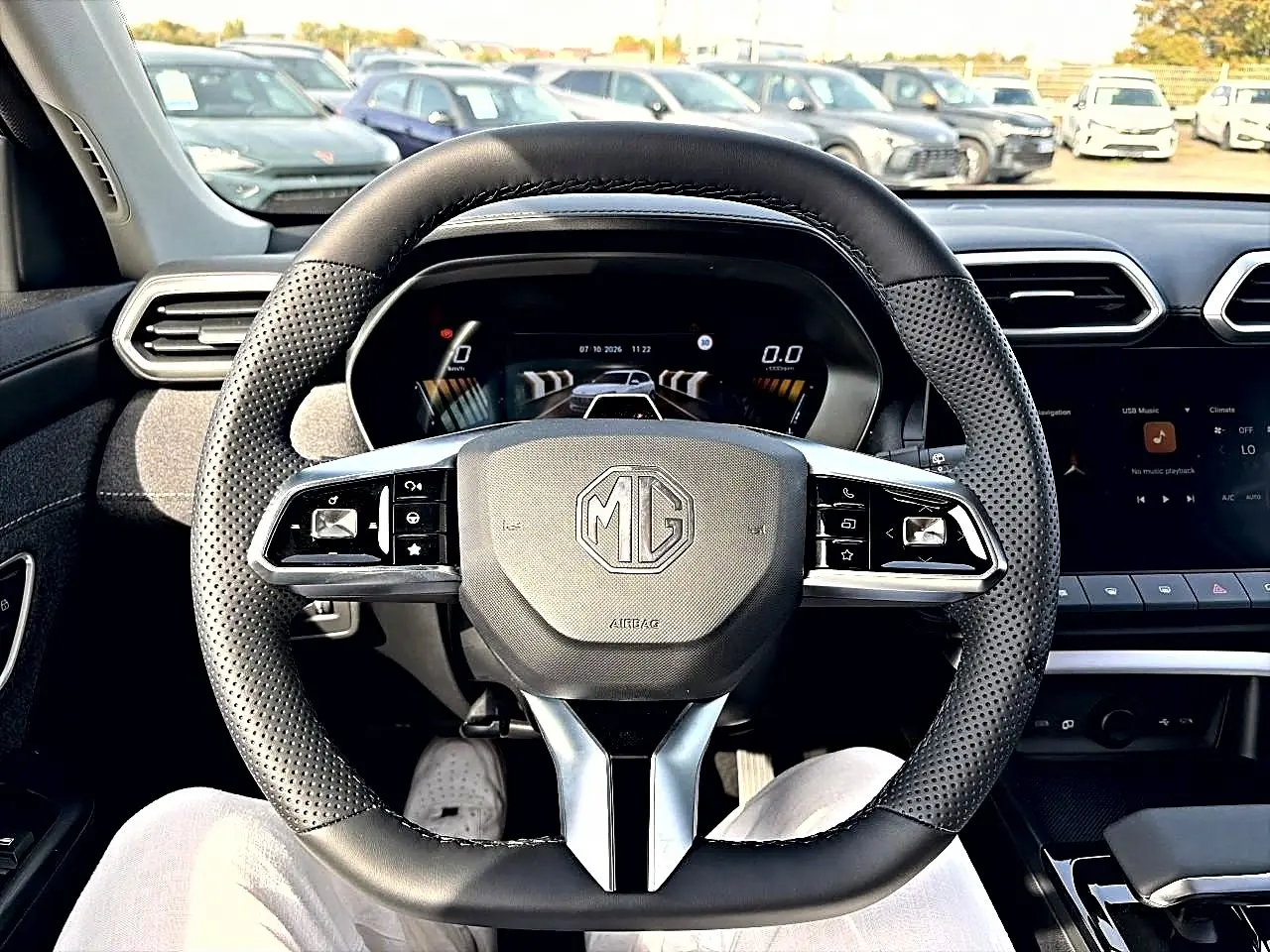 Vue intérieure centrée sur le volant noir perforé du MG ZS 1.5 hybrid 2026 avec tableau de bord numérique et écran tactile.