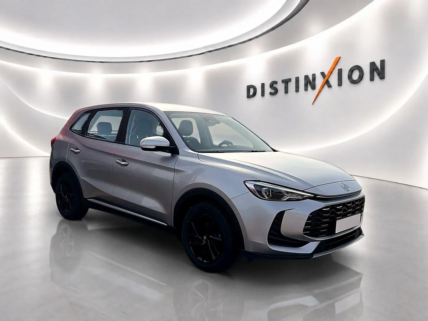 Vue 3/4 avant du SUV MG ZS Cosmic Silver 2026 avec jantes noires, dans un showroom lumineux moderne.
