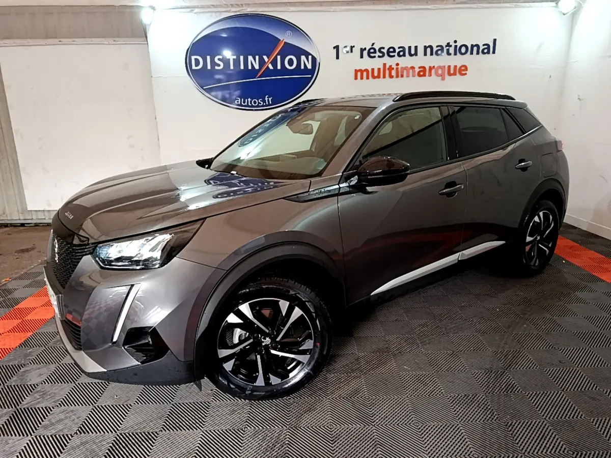 Peugeot 2008 gris foncé en 3/4 avant droit, avec jantes noires et toit noir dans un showroom intérieur.