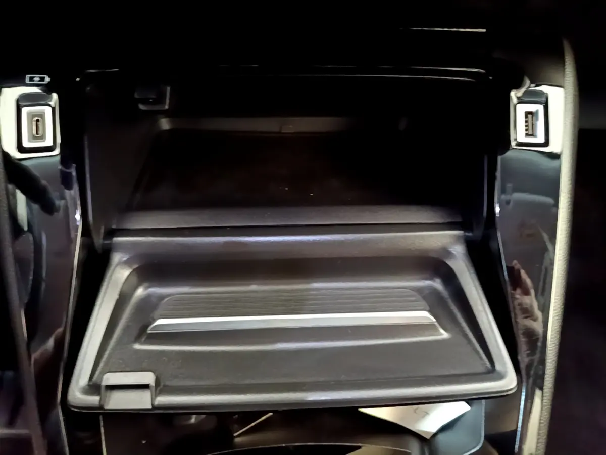 Gros plan sur la boîte à gants ouverte avec ports USB visibles dans l’habitacle noir du Peugeot 2008 gris foncé.