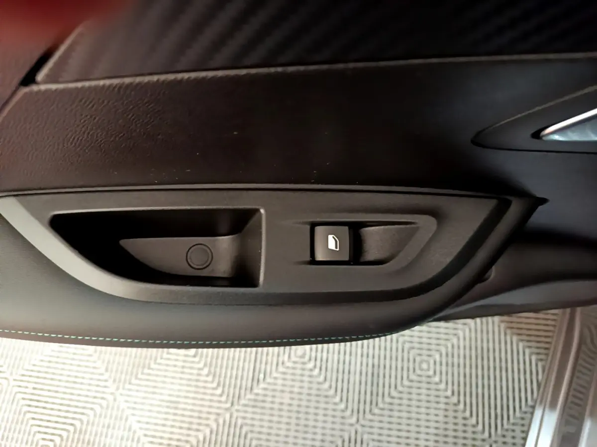 Gros plan sur la commande d'ouverture de trappe à carburant dans l'habitacle noir du Peugeot 2008 gris foncé.