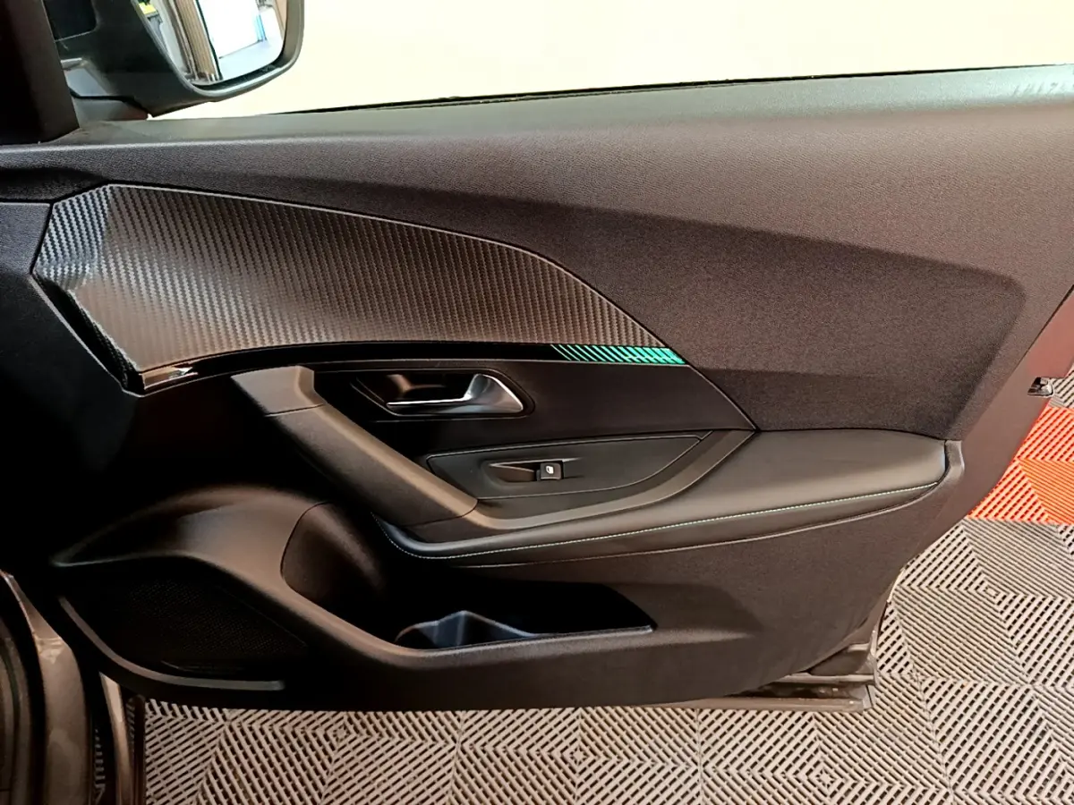 Vue côté gauche de la porte intérieure noire avec insert effet carbone du Peugeot 2008 gris foncé 2022 PureTech Allure.