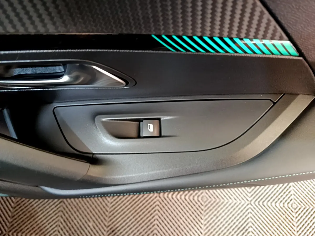 Détail de la commande de lève-vitre côté conducteur avec insert décoratif turquoise sur porte noire du Peugeot 2008 gris foncé.