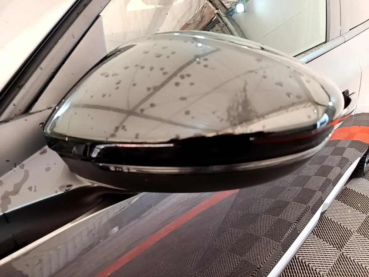 Rétroviseur droit gris foncé du Peugeot 2008 PureTech 130 en gros plan avec reflet du plafond et carrosserie visible.