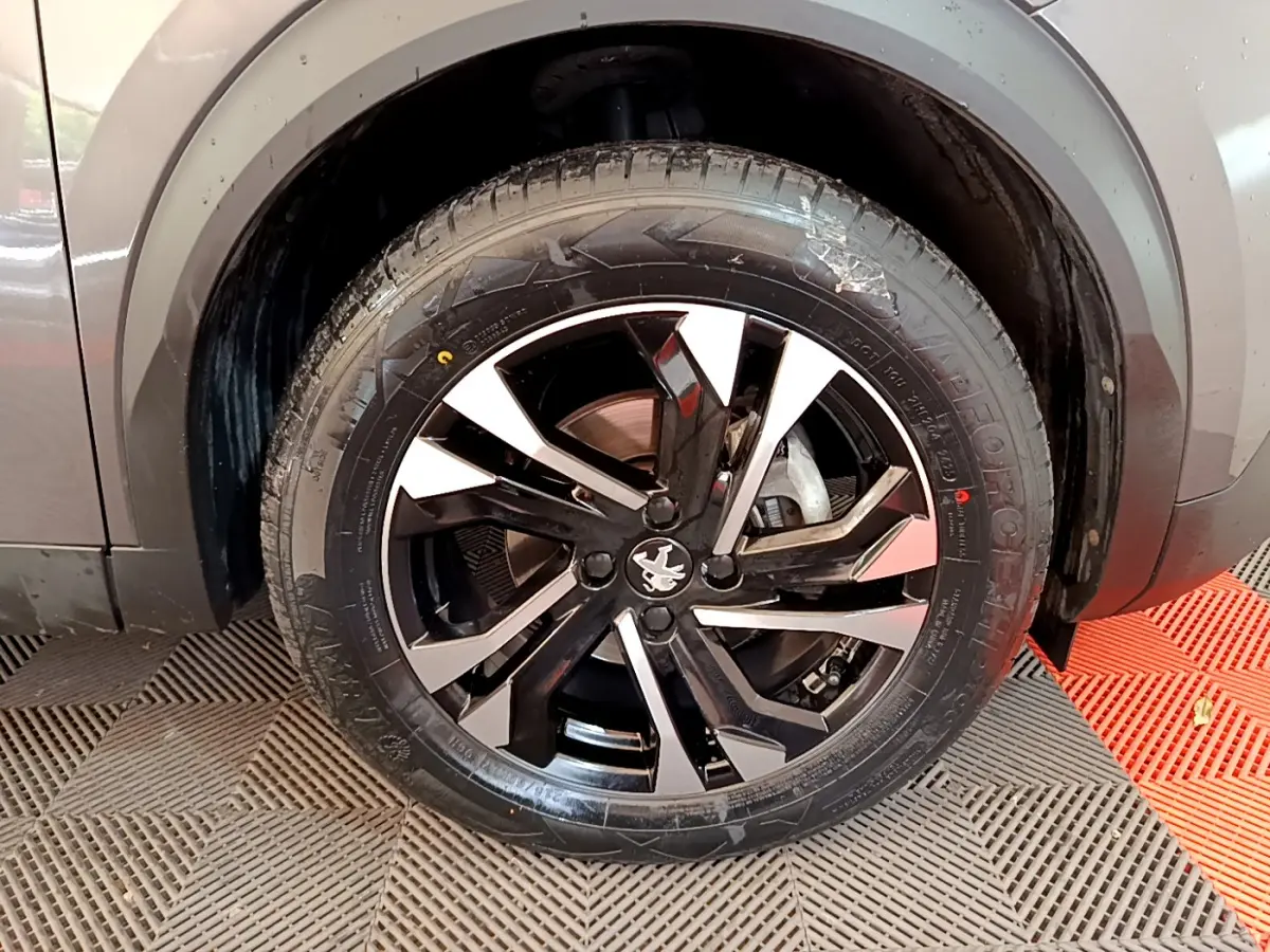 Gros plan sur la roue avant droite gris foncé du Peugeot 2008 avec jante alliage noire et argentée au design moderne.