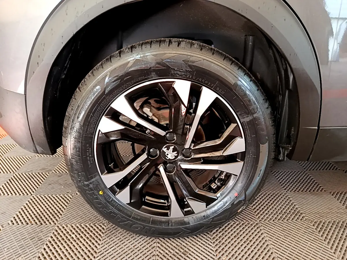 Gros plan sur la roue avant droite du Peugeot 2008 gris foncé avec jante alliage noire et argentée.
