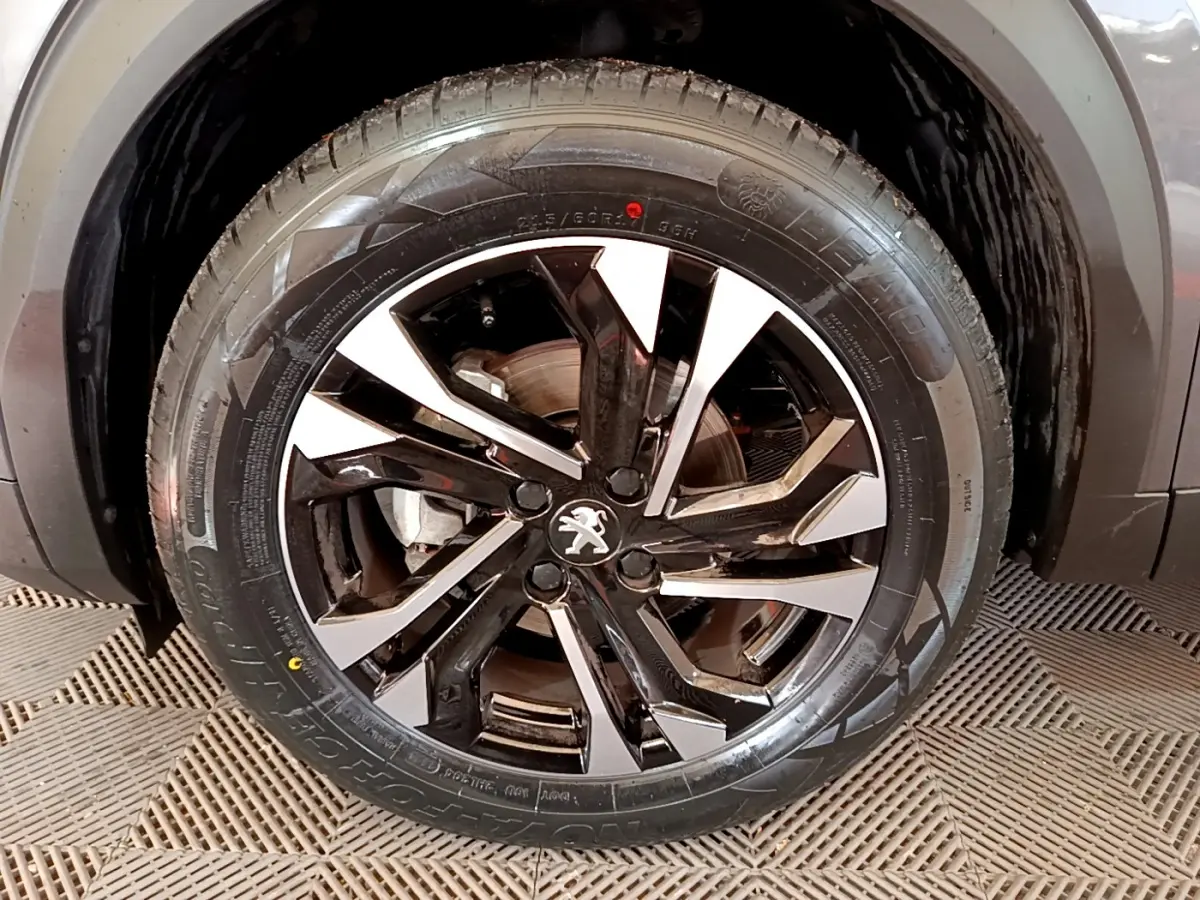 Gros plan sur la roue avant droite du Peugeot 2008 gris foncé avec jante alliage bicolore au design moderne.