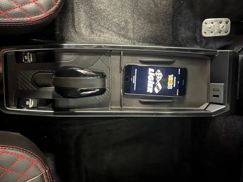 Vue plongeante sur la console centrale noire du Ligier JS50 Sport Ultimate 2025 avec levier de vitesses manuel et smartphone posé.