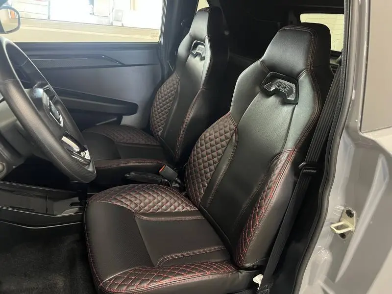 Vue intérieure côté gauche du LIGIER JS50 SPORT ULTIMATE E5+ 2025, sièges noirs en cuir avec surpiqûres rouges et détails sportifs.