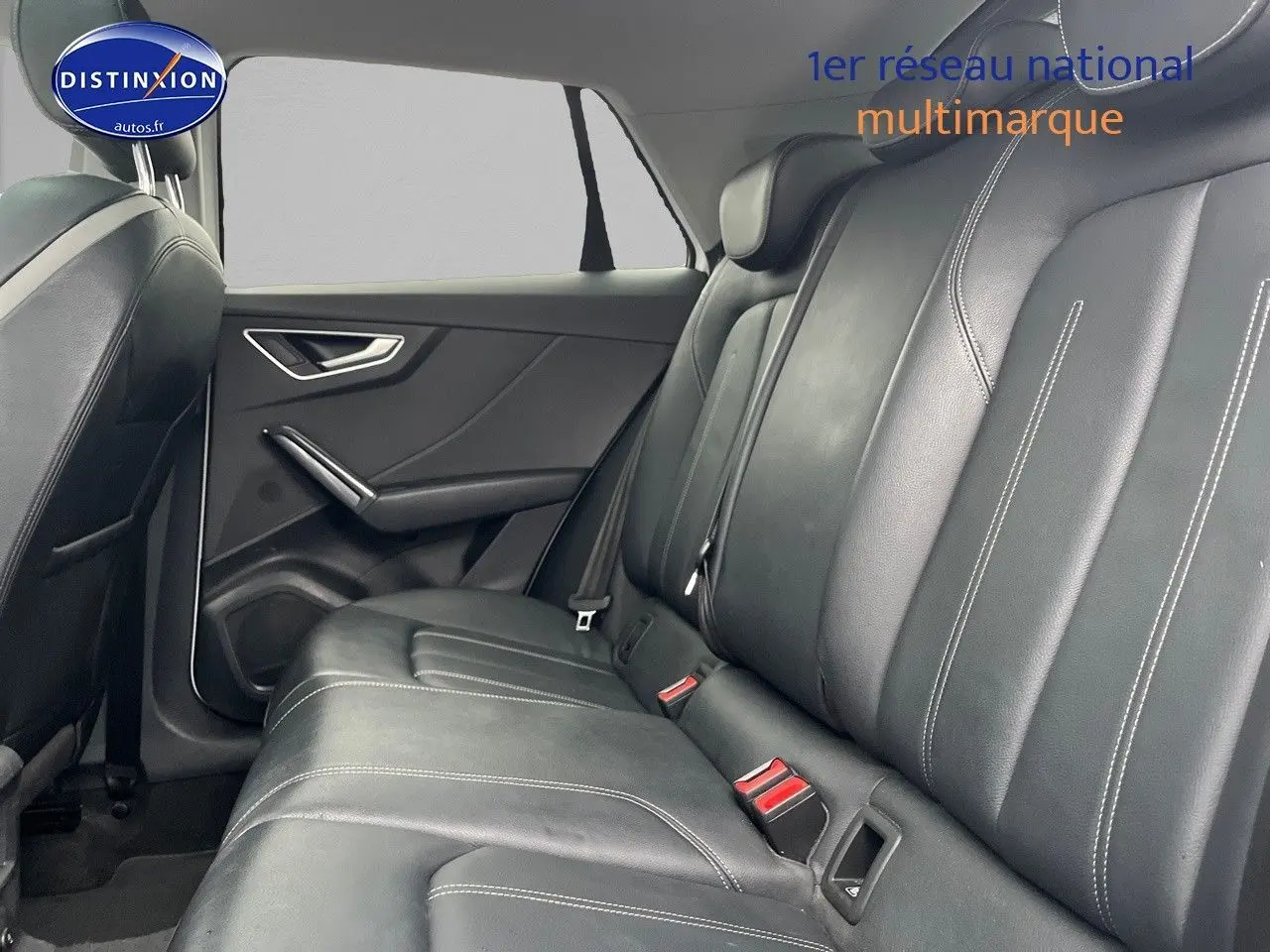 Vue intérieure du siège arrière en cuir noir avec surpiqûres blanches d'un Audi Q2 blanc, côté gauche visible.