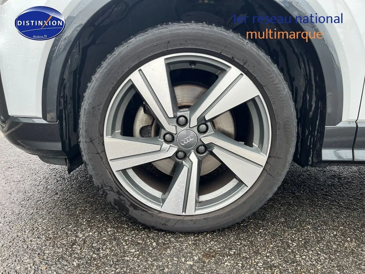 Gros plan sur la jante alu 18 pouces style 5 branches du côté gauche d’un Audi Q2 blanc Ibis.