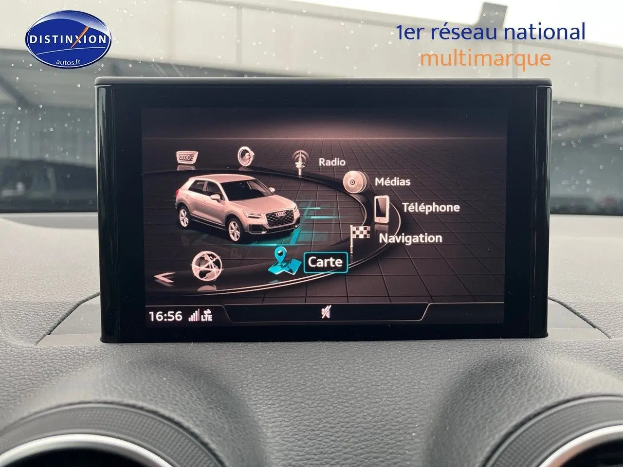 Écran central montrant l'interface multimédia avec une image 3D de l'Audi Q2 blanc Ibis en vue latérale.