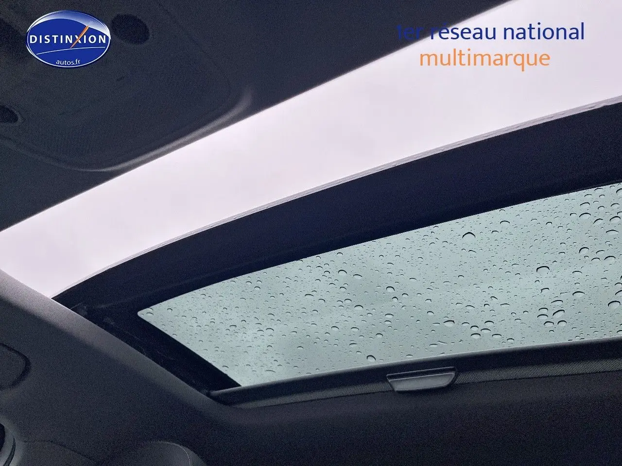 Toit ouvrant électrique panoramique avec gouttes de pluie sur Audi Q2 blanc Ibis, vue intérieure vers le ciel.