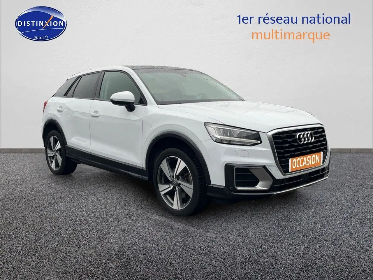 Audi Q2 blanc Ibis vu en 3/4 avant droit, avec jantes alliage 18 pouces et toit ouvrant électrique.