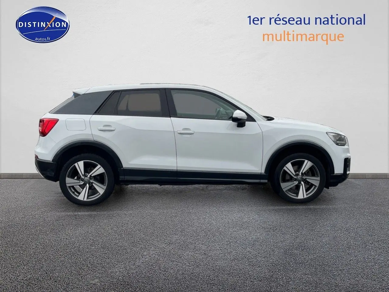 Profil droit d'un Audi Q2 blanc Ibis avec jantes 18 pouces et vitres surteintées sur fond neutre.