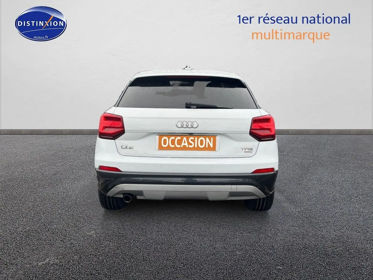 Vue arrière d’un Audi Q2 blanc Ibis avec vitres surteintées et plaque d’immatriculation orange « OCCASION ».