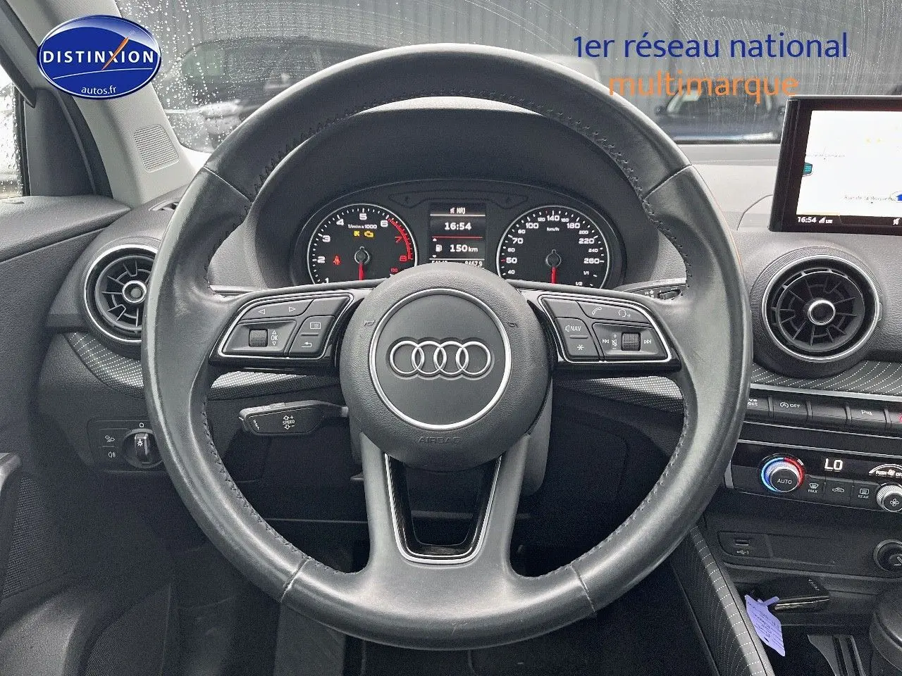 Vue centrée sur le volant cuir multifonction noir de l'Audi Q2 2018 avec tableau de bord et écran multimédia.