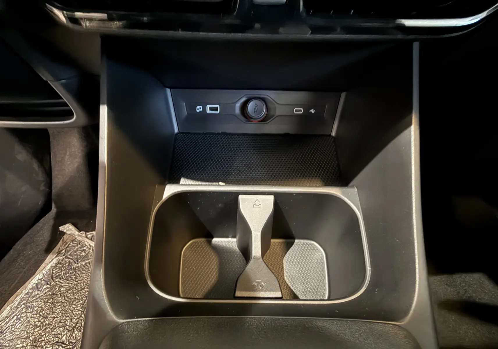 Vue rapprochée de la console centrale noire du MG3 1.5 L Hybrid+ 195 ch Luxury avec porte-gobelets et prise 12V.