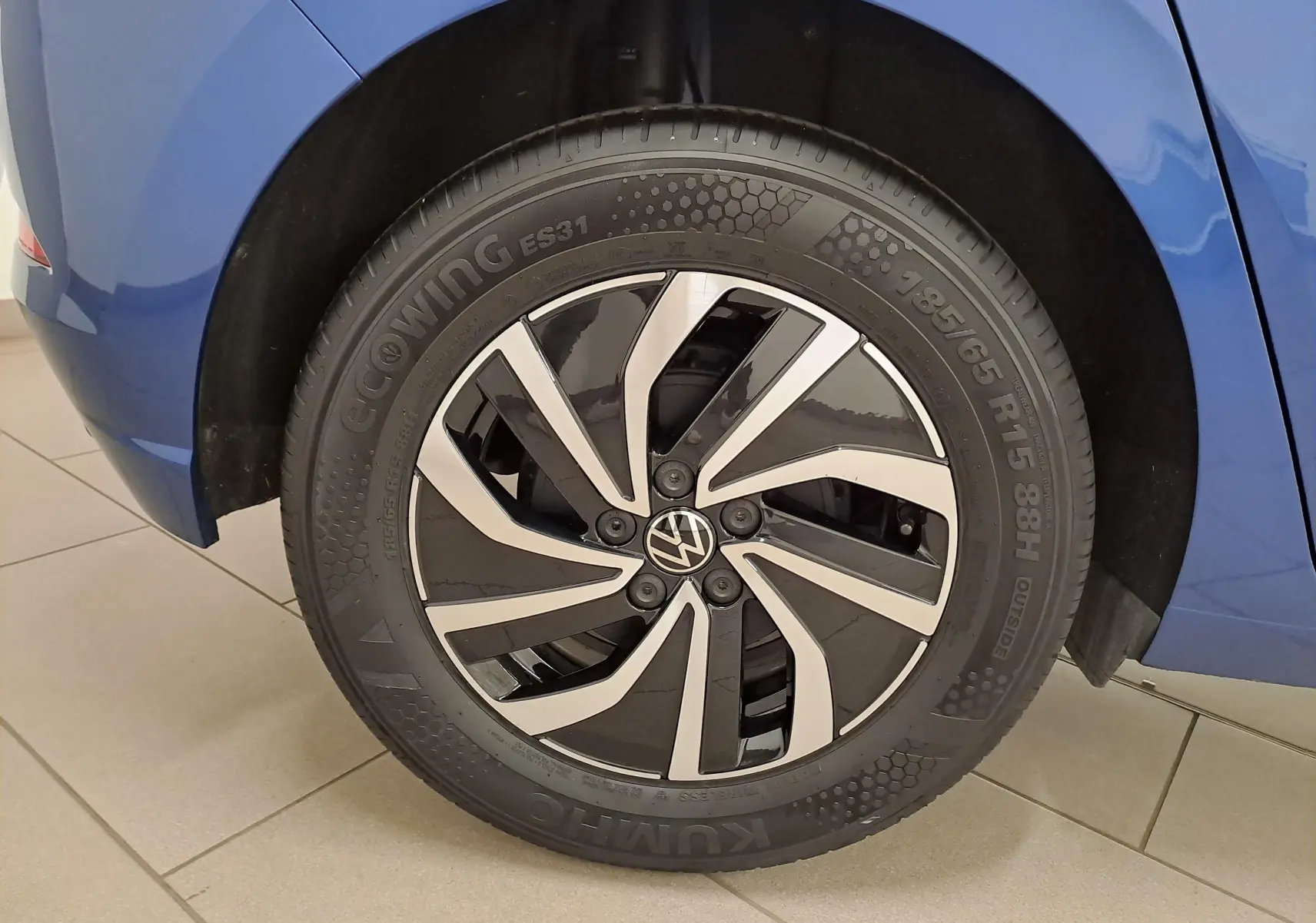 Gros plan sur la roue avant droite d'une Volkswagen Polo Bleu Récif avec jante alliage noir et argent.