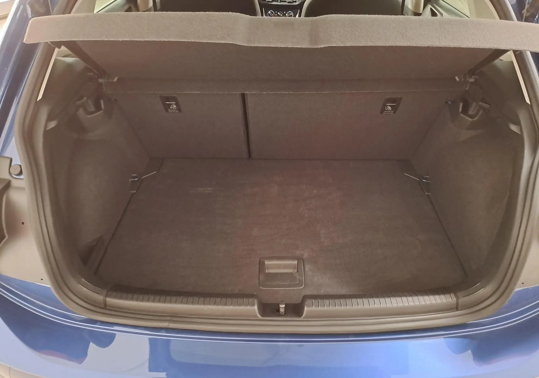 Vue arrière du coffre ouvert d'une Volkswagen Polo 2025 bleu récif, montrant un espace de rangement propre et spacieux.