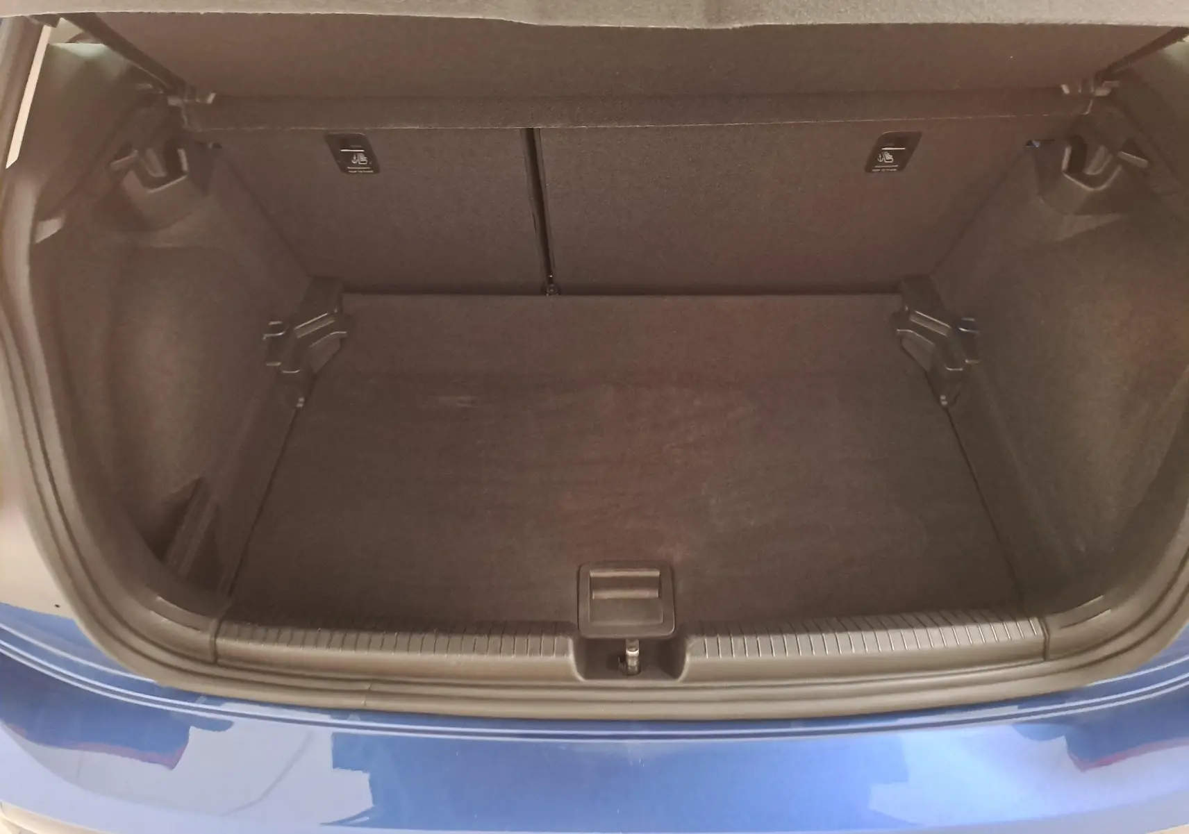 Coffre ouvert vu de dessus d'une Volkswagen Polo 2025 bleu récif, intérieur noir et espace de rangement vide.