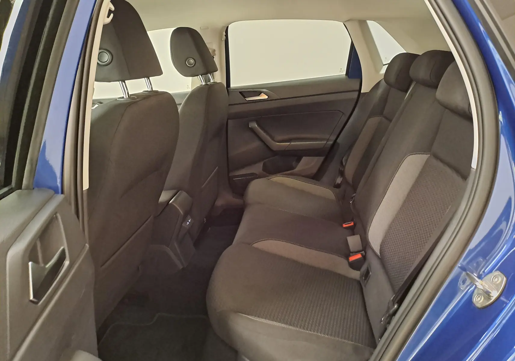Vue intérieure arrière côté gauche de la Volkswagen Polo Bleu Récif montrant les sièges arrière en tissu noir et gris.