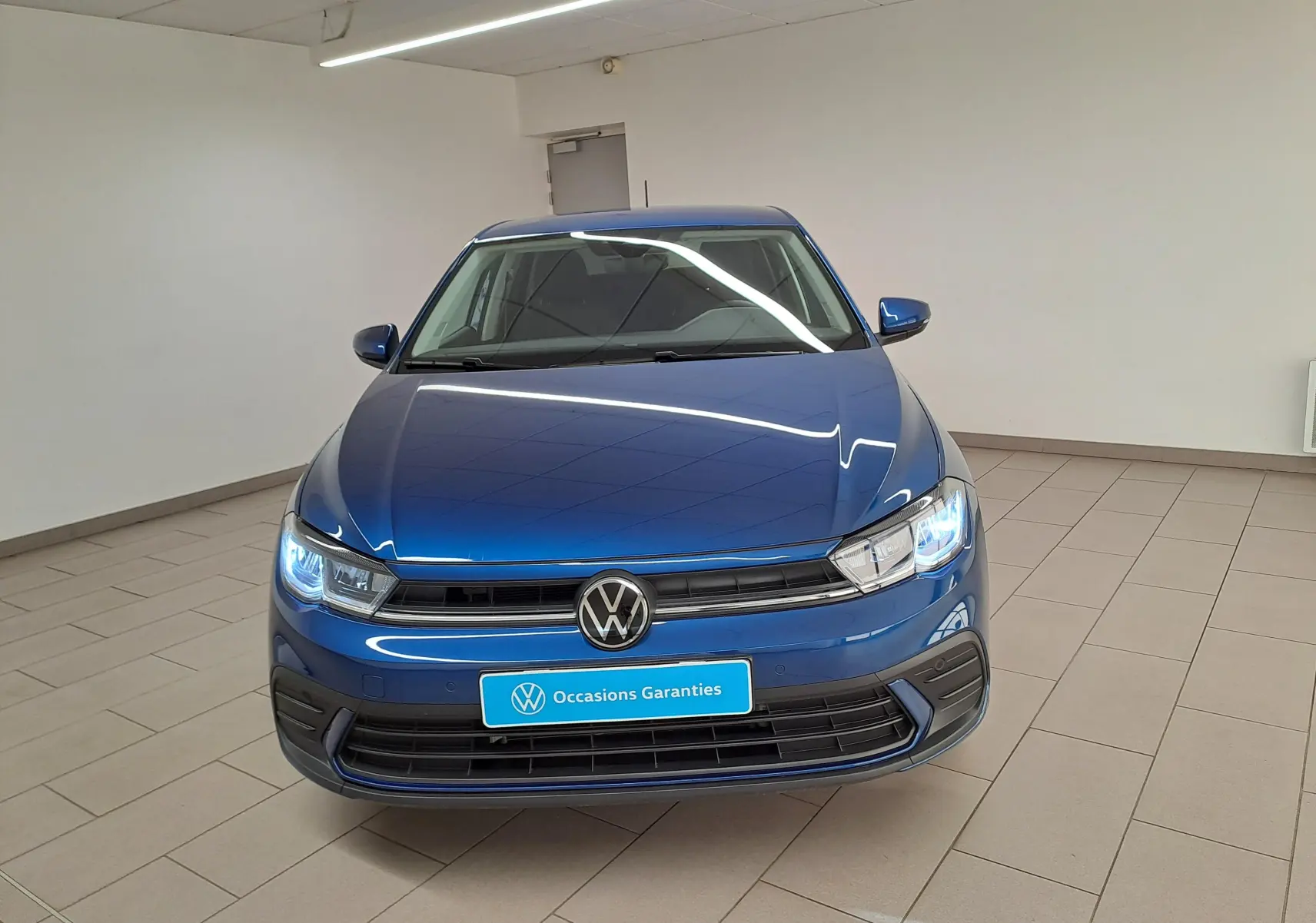 Volkswagen Polo 1.0 TSI 95 VW Edition bleu récif vue de face avec phares LED allumés en intérieur.