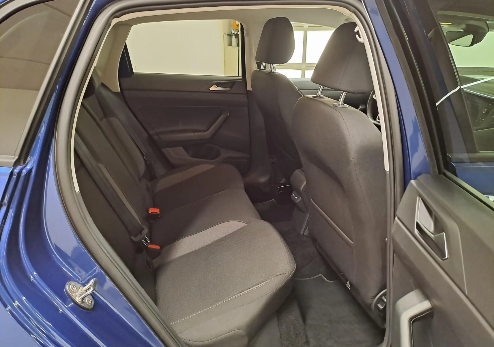 Vue intérieure côté gauche de la banquette arrière noire d'une Volkswagen Polo Bleu Récif avec portière ouverte.