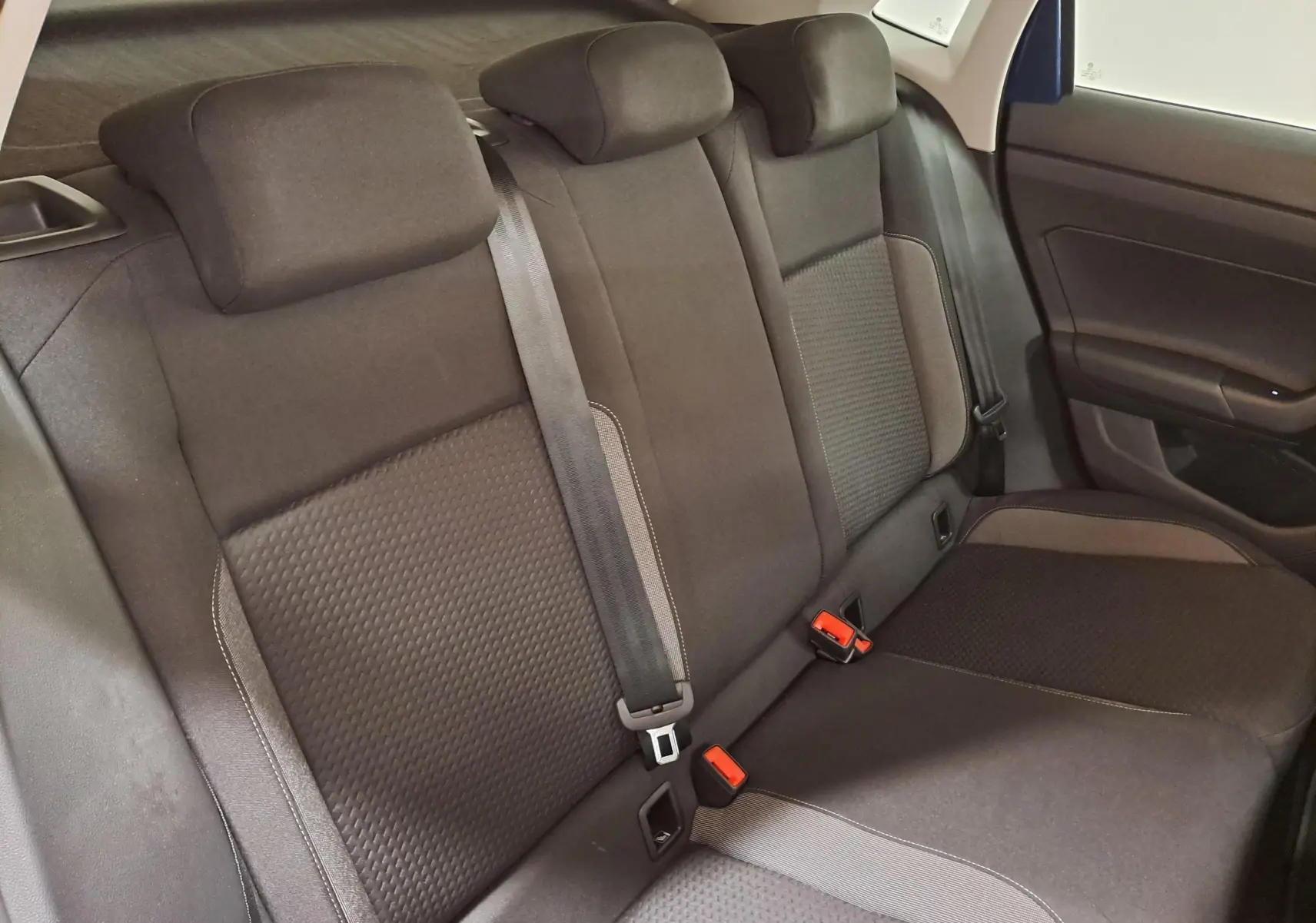 Vue intérieure de la banquette arrière de la Volkswagen Polo 2025 avec sièges noirs et ceintures de sécurité visibles.