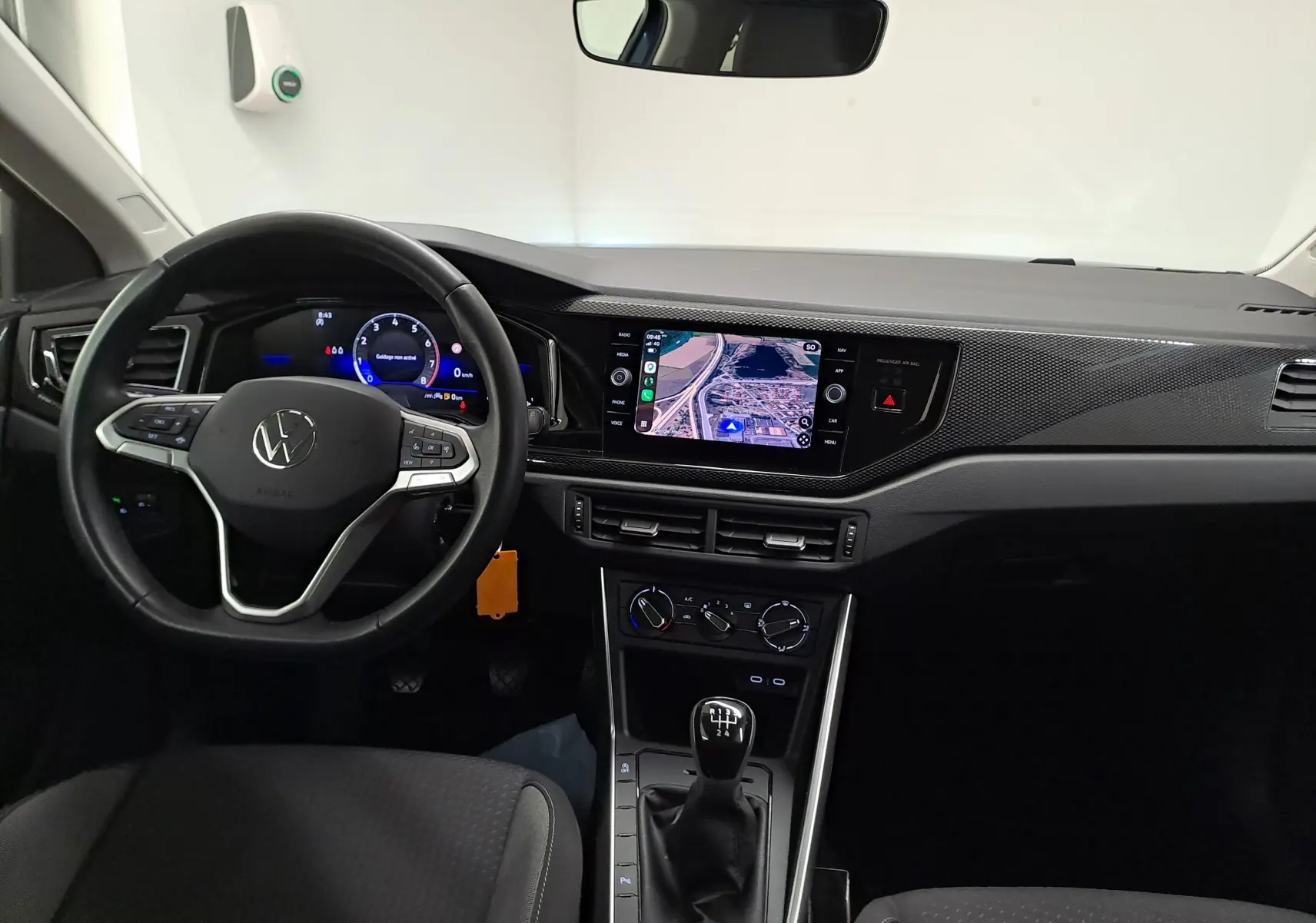 Vue intérieure avant du tableau de bord et volant cuir noir d'une Volkswagen Polo 2025 avec écran tactile et levier de vitesses manuel.