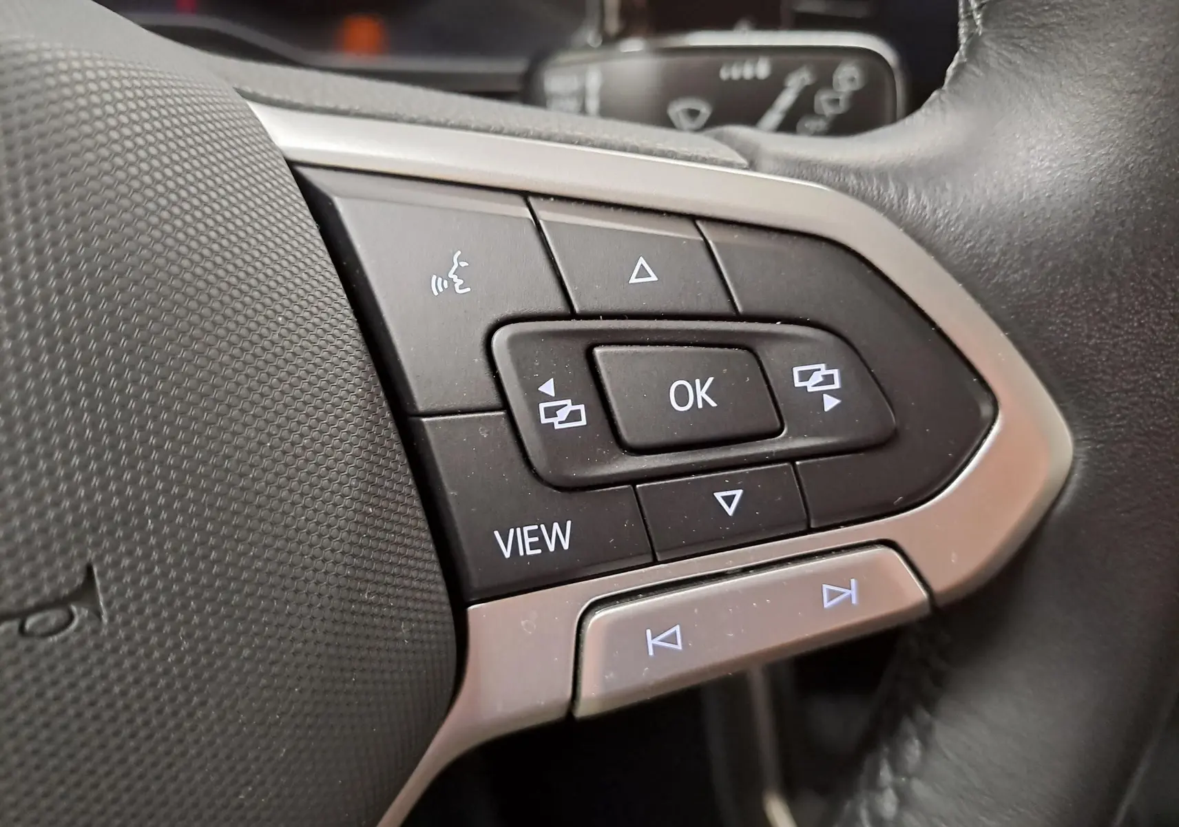 Gros plan sur les commandes multifonctions du volant cuir de la Volkswagen Polo 1.0 TSI 95 VW Edition, boutons rétroéclairés.