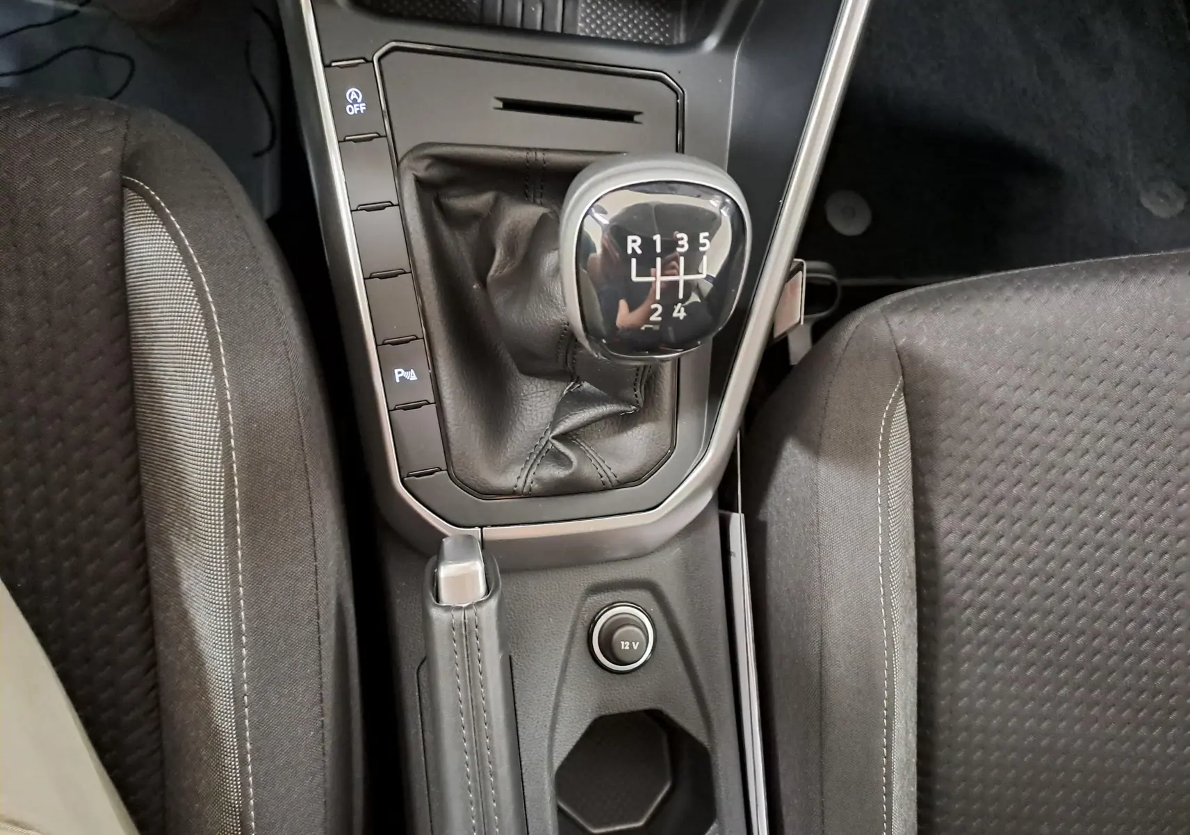 Vue plongeante sur la console centrale de la Volkswagen Polo 1.0 TSI, levier de vitesse manuel et frein à main en cuir noir.