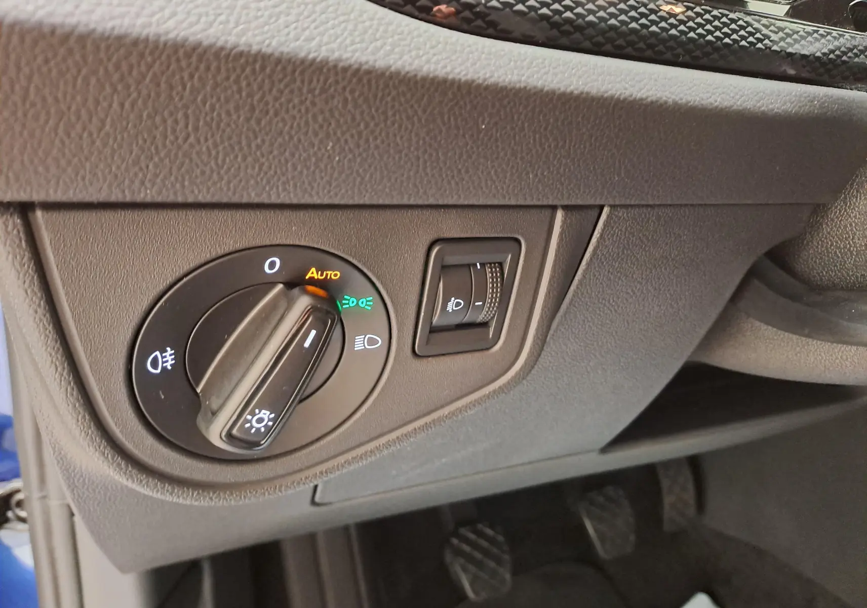 Gros plan sur le bouton de commande des phares et réglage d'éclairage intérieur dans l'habitacle gris du Volkswagen Polo Bleu Récif.