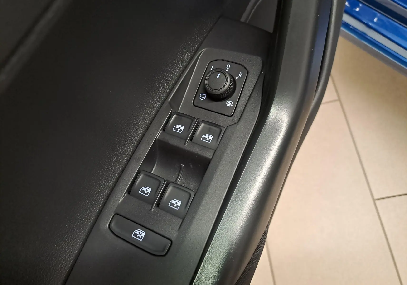 Gros plan sur les commandes des vitres électriques et rétroviseurs sur la porte côté conducteur d'une Volkswagen Polo Bleu Récif.