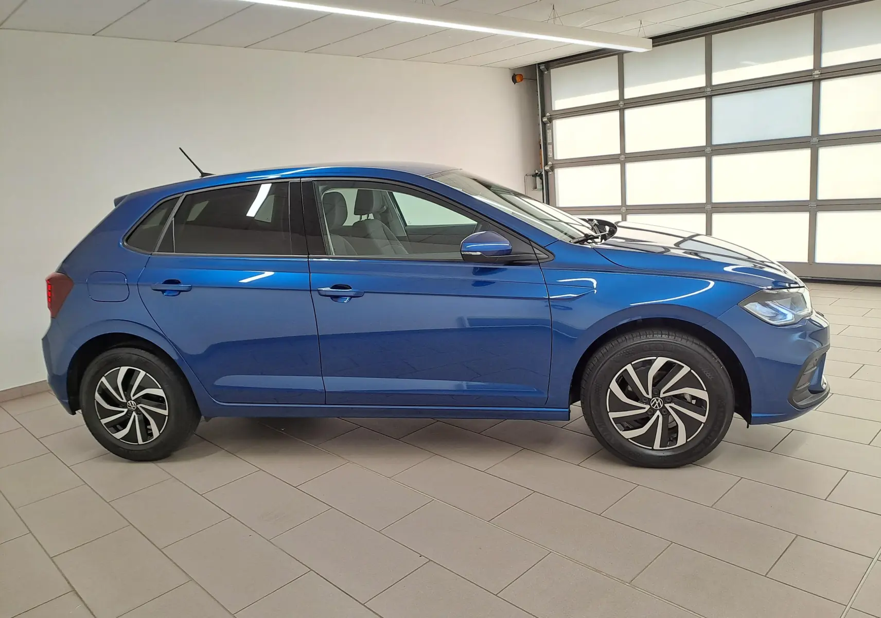 Vue latérale droite d'une Volkswagen Polo 1.0 TSI 95 VW Edition en bleu récif, avec jantes alliage et vitres surteintées.