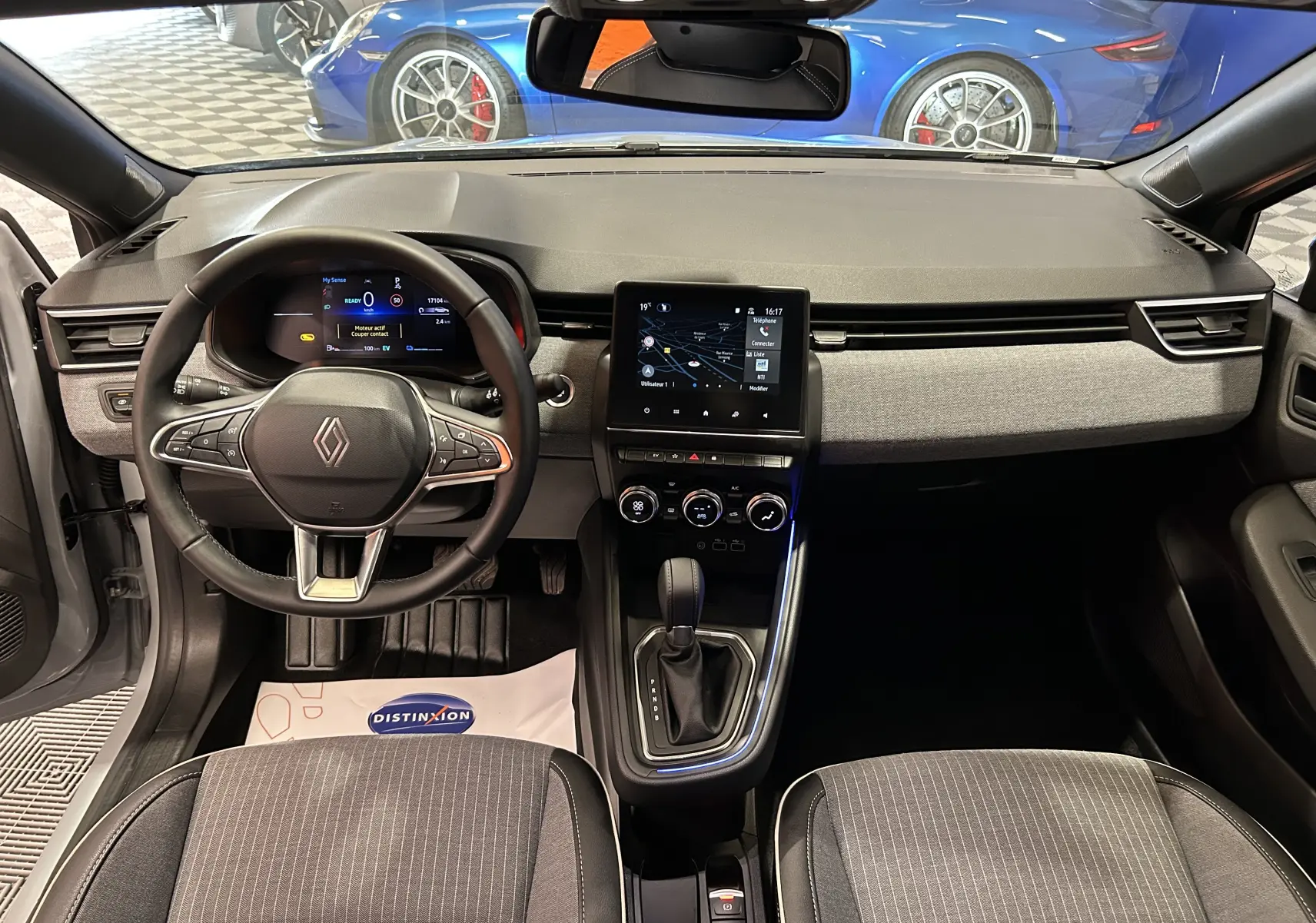 Intérieur de la Renault Clio V hybride 2025, vue frontale du tableau de bord avec écran tactile et volant multifonction.
