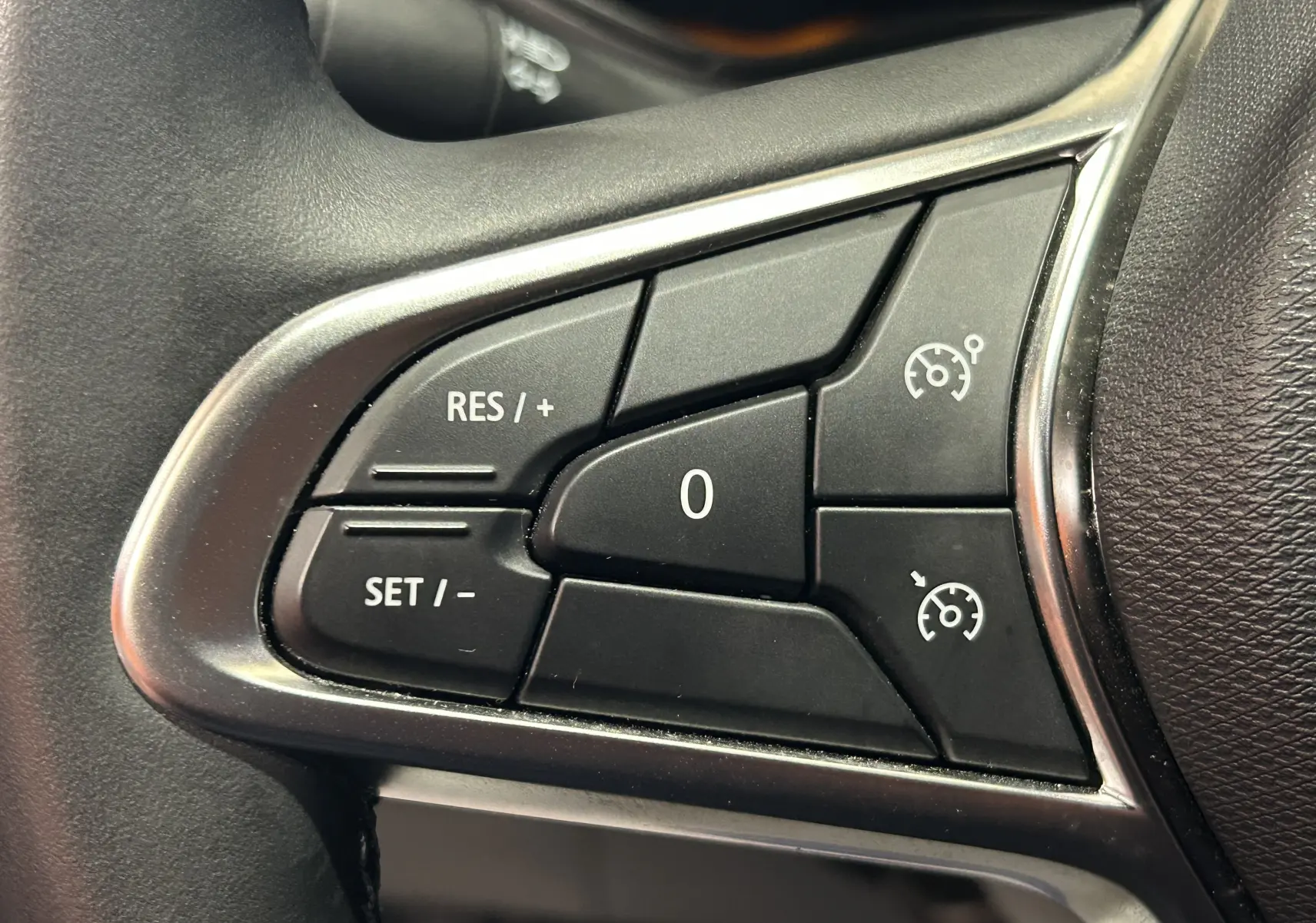 Gros plan sur les commandes de régulateur de vitesse au volant d'une Renault Clio V gris Rafale métal.