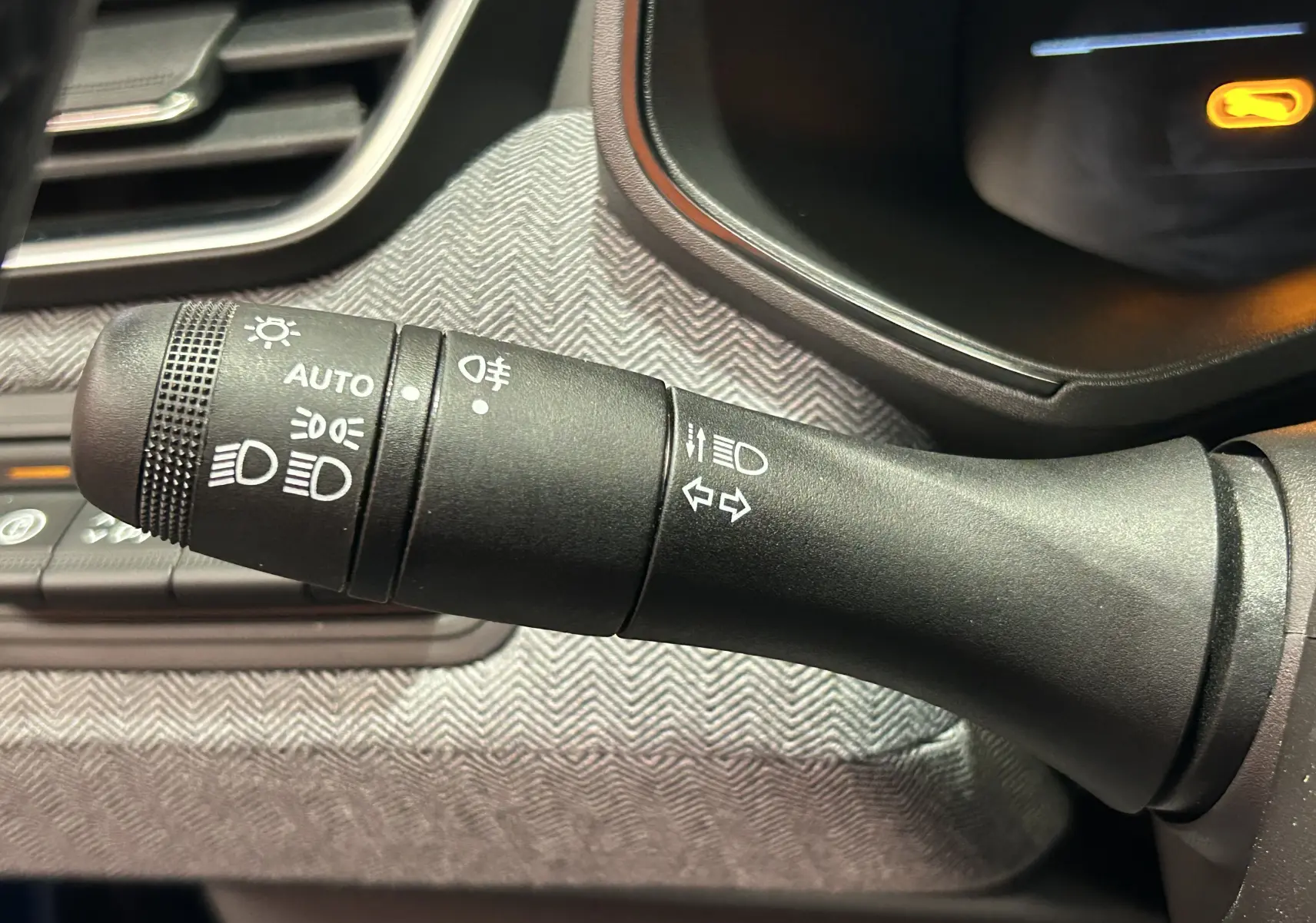 Gros plan sur la commande des phares et clignotants dans l’habitacle du Renault Clio V hybride, finition gris Rafale.