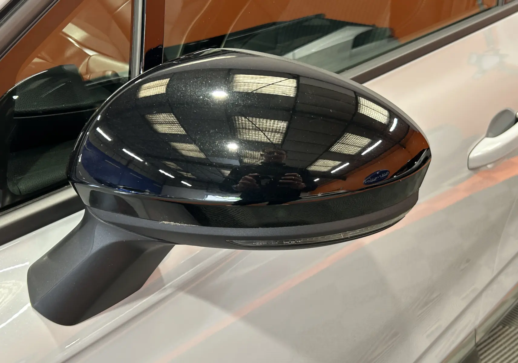 Rétroviseur droit noir brillant sur Renault Clio V gris Rafale Métal, vue rapprochée en intérieur showroom.