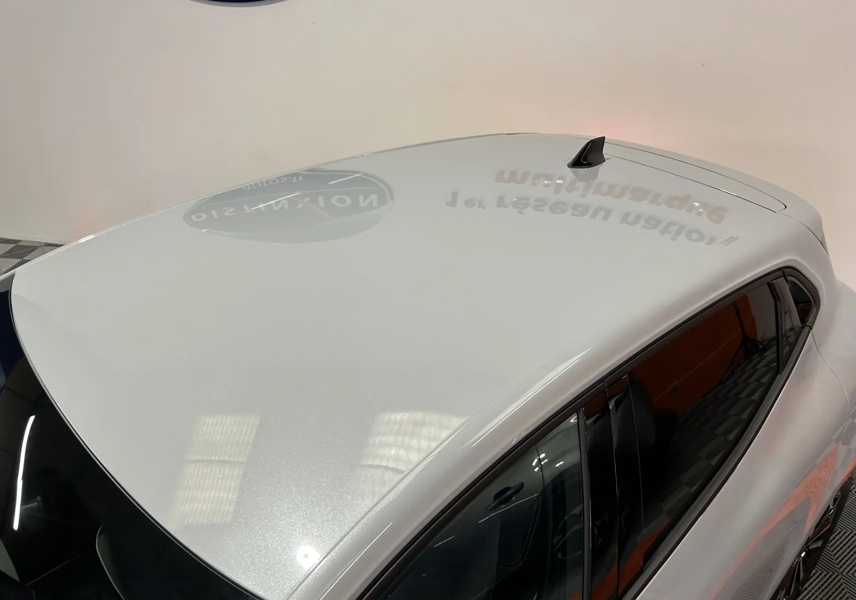 Vue plongeante sur le toit gris métal brillant d'une Renault Clio V hybride, avec antenne requin noire visible.