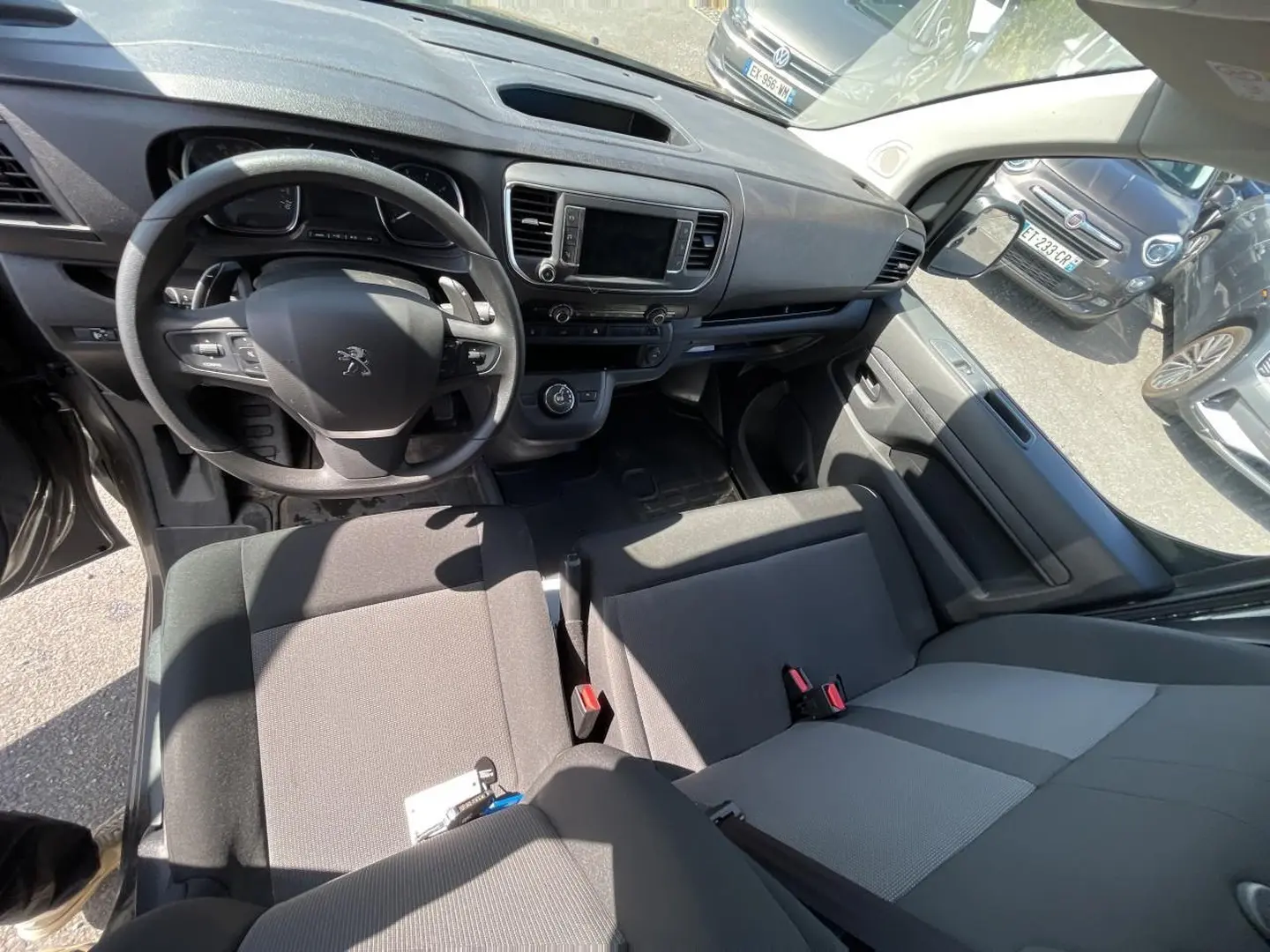 Vue intérieure du poste de conduite du Peugeot Expert Fourgon gris, avec volant multifonctions et banquette bi-ton noir/gris.