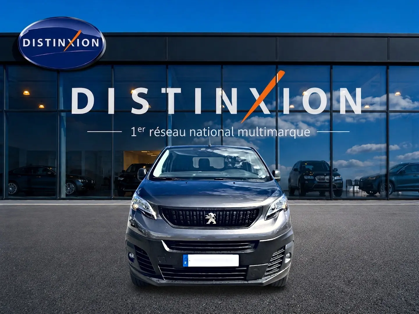 Vue de face du Peugeot Expert Fourgon gris 2024, devant une vitrine avec logo Distinxion en arrière-plan.